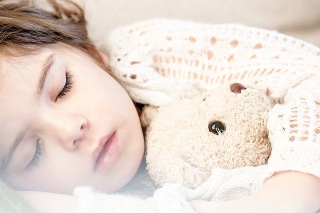 A girl sleeping while holding a teddy bear