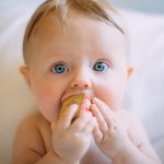 A baby eating a fruit with their hands